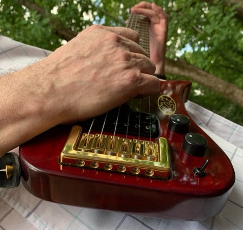 Action shot of Gold Compact Bridge in Red Trouper travel Guitar